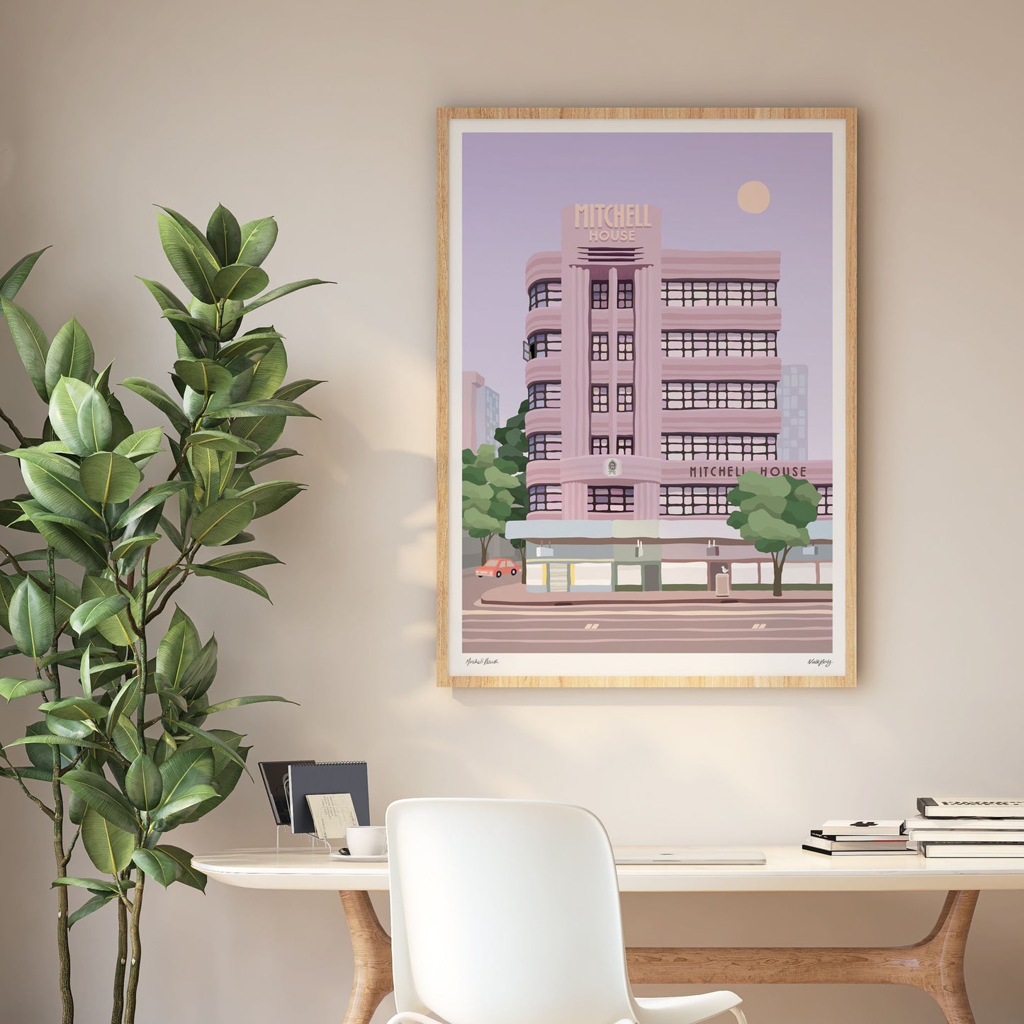 Large wood framed print of colourful illustration of Mitchell House Melbourne city streetscape hanging over a desk