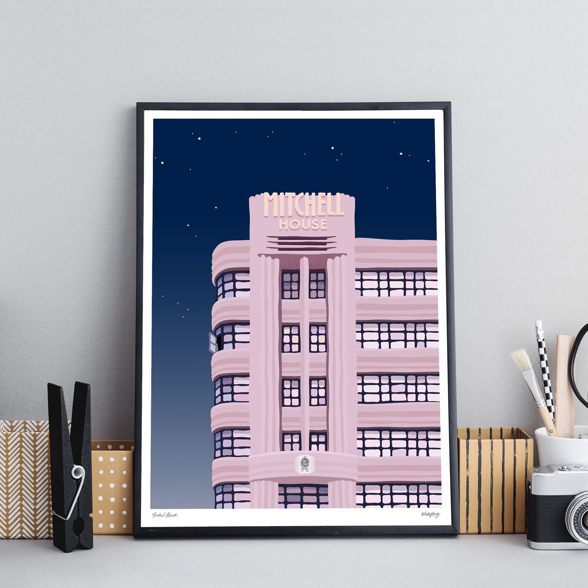 Colourful art print of Mitchell House Melbourne at night starry sky black framed print on office desk
